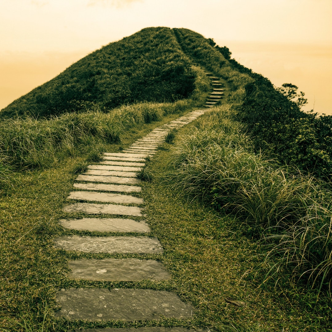 A path leading up to the top of a large grassy hill to depict navigating your personal growth journey.