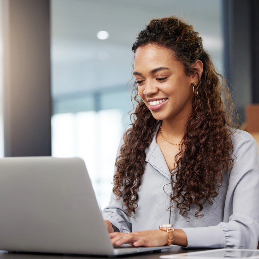 Black woman with chronic illness sitting in her office smiling in front of a laptop while working with a therapist who gets it.