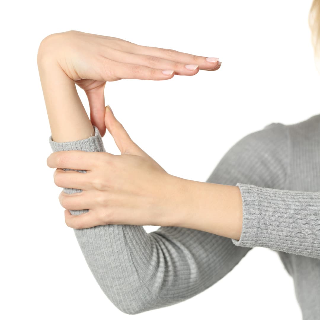 A photo of a woman's right arm with her left hand holding her thumb against her forearm to demonstrate testing for hypermobile ehlers-danlos syndrome with the Beighton Scale.