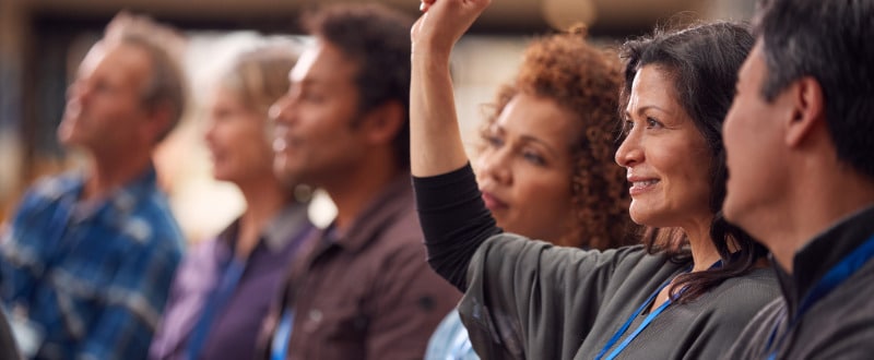 A woman at a parenting class raises her hand to ask a question about making good parenting choices.