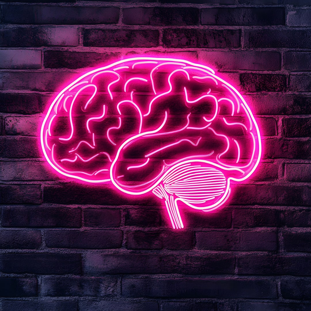 A depiction of a human brain in pink neon lights against a dark brick wall to represent the acceptance of neurodiversity affirming counseling.