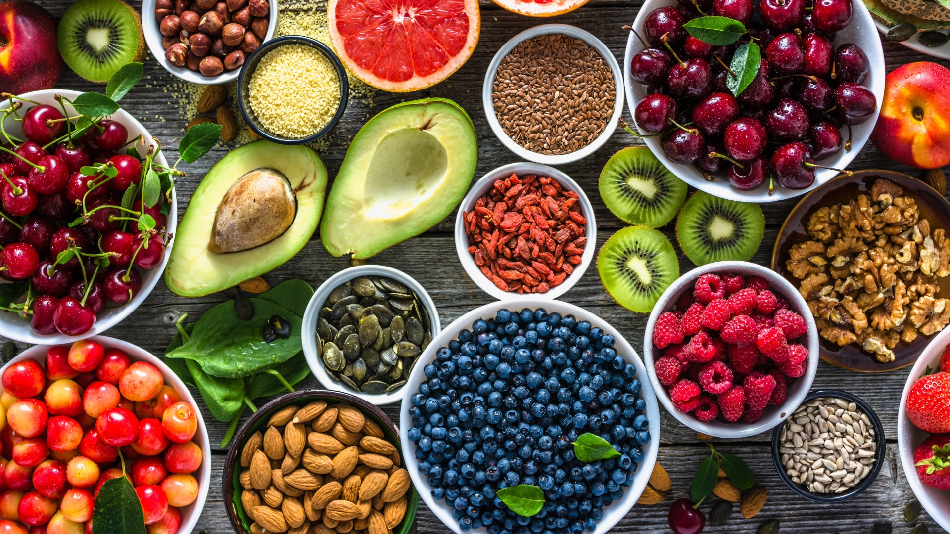 Photo of many healthy foods including nuts, seeds and berries in small bowls laid out to show foods that support healing and are good for nurturing resilience. 