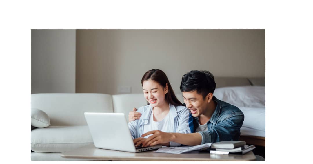 A young Asian couple sitting on the floor together at a coffee table engaging in solution focused approaches for relationship issues with their counselor online.