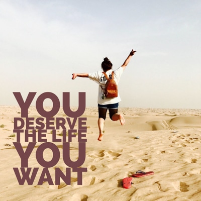 Woman with a backpack running across the sand and leaping showing that you deserve a good life. The caption reads: you deserve the life you want